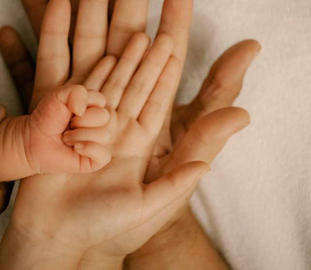 a families of four's hands laid one on top of the other from largest to smallest