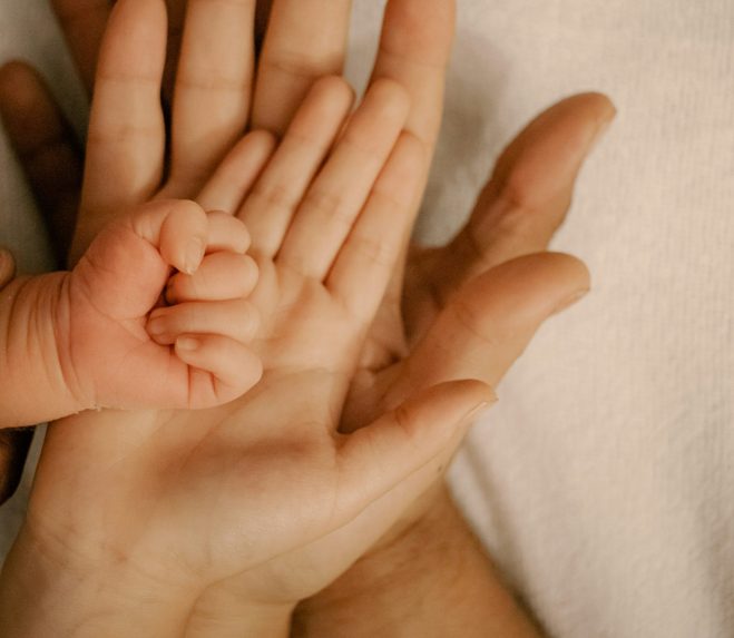 a families of four's hands laid one on top of the other from largest to smallest