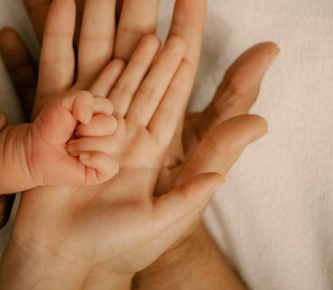 a families of four's hands laid one on top of the other from largest to smallest